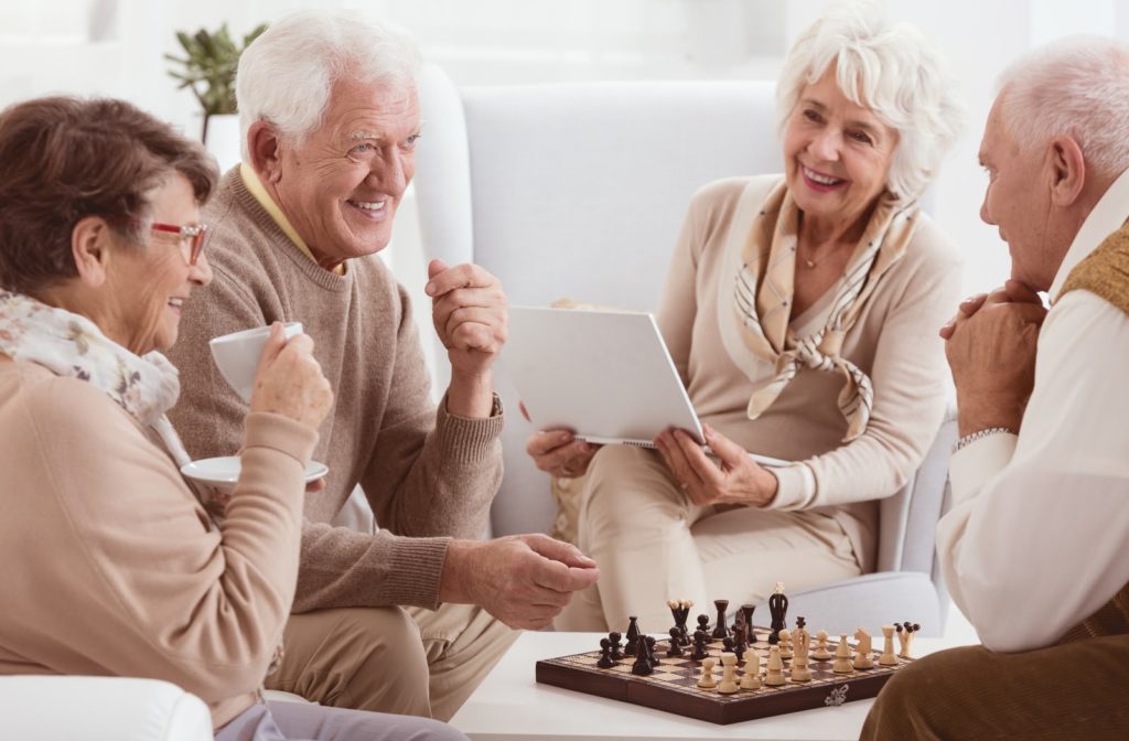 Happy seniors socializing and playing chess at senior home community.