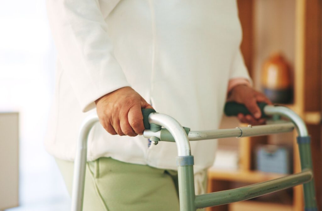 A close-up of an older adult's hand gripping their walker for added stability and support while walking.