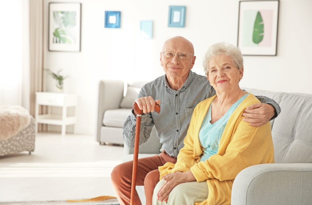 An older couple in assisted living sitting together and smiling at the camera.