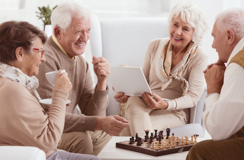 Happy seniors socializing and playing chess at senior home community.