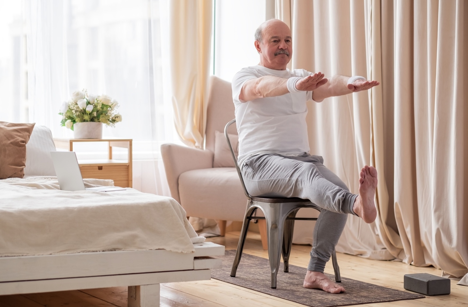A senior performing seated leg lift exercises to improve balance.