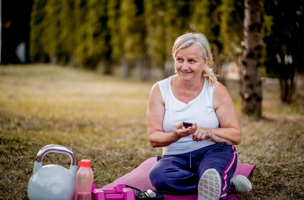  A happy senior checks their blood sugar levels before starting an outdoor exercise class